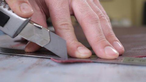 Craft factory authentic. Close-up shot of craft master cutting leather with utility knife. Handmade and leatherwork concept. Manufacturing leather process in small private factory. 4 k video
