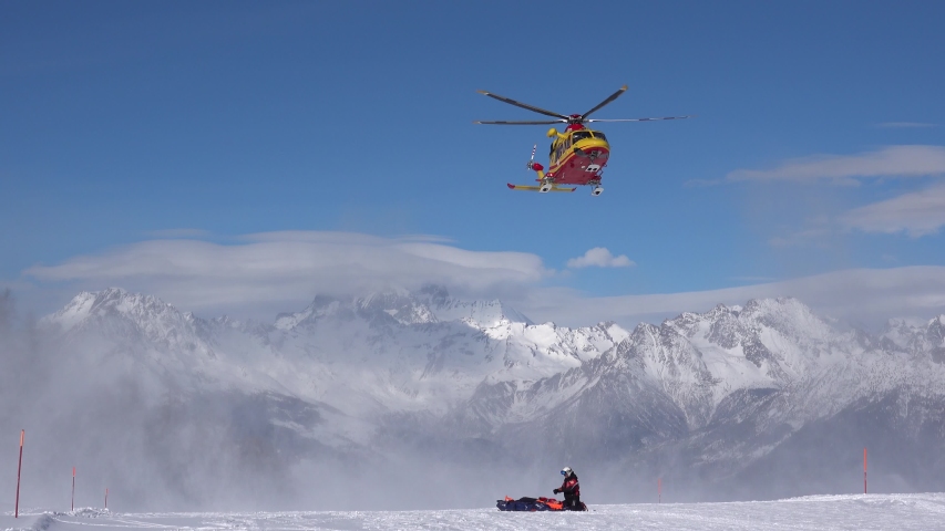 Rescue yellow helicopter landing after emergency on ski slopes