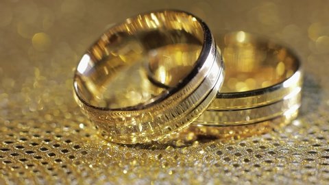 Wedding gold rings lying on shiny glossy surface. Shining with light. Close-up, macro shot