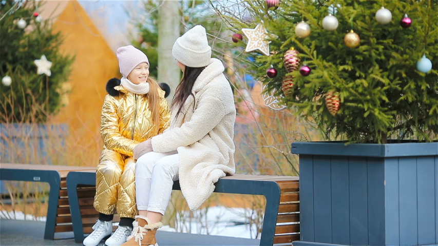 Family winter sport. Mother with little daughter ready to skate on ice-rink