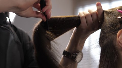 Young woman getting her hair dressed in hair salon. Hairdresser at salon combing hair comb girl brunette. 4K slow motion. 