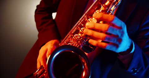 An experienced musician playing saxophone in jazz band. Saxophonist performing a solo in club stage - music, arts concept 4k footage