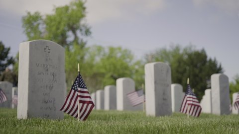 Denver, Colorado, USA-May 26, 2019 - Small American Flags next to white marble gravestones at the  Fort Logan National Cemetery on Memorial Day.