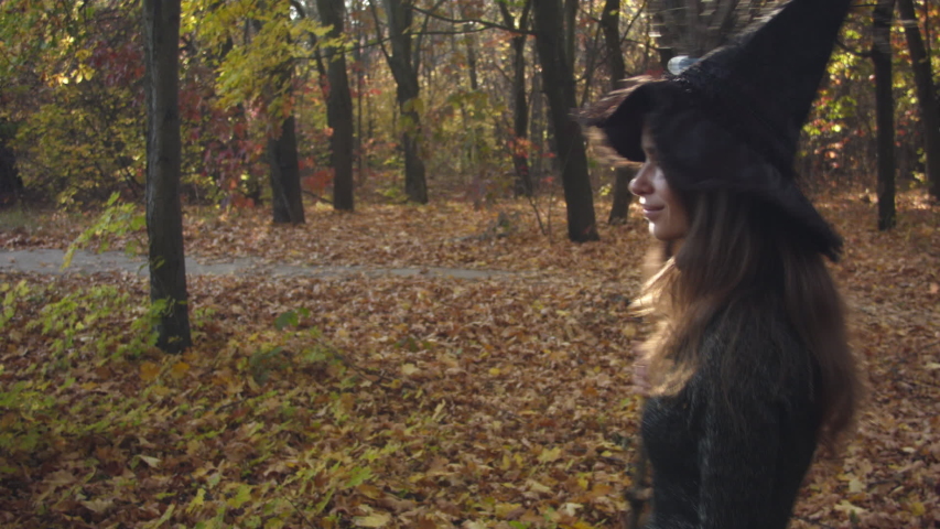 Young caucasian woman in halloween costume resting in the autumn forest. Witch with a broom in the forest. Recorded in Raw on Blackmagic camera.