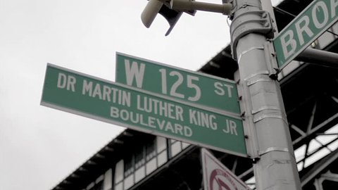NEW YORK - FEB 9, 2010: 125 and Martin Luther King Blvd sign, gritty vintage style archival 35mm film footage in Harlem NY. Harlem is a famous neighborhood in Uptown Manhattan, NYC.
