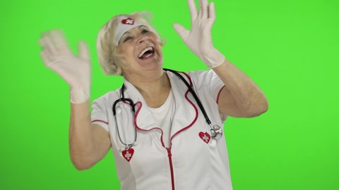 Portrait of elderly caucasian female doctor dance. Crazy and funny nurse. Green screen. Chroma key