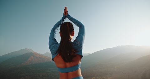 Athletic girl training in mountains during sunrise. Fit model doing various yoga poses during her meditation session - healthy living concept 4k footage