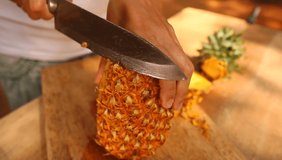 video cutting ripe pineapple with a knife on a table in sri lanka
