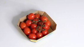 Woman using food film for food storage on a white table. Roll of transparent polyethylene food film for packing products. cherry tomatoes in disposable plastic packaging Slow Motion video. Close up
