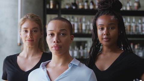 Portrait of female owner of restaurant bar with team of female waiting staff standing by counter - shot in slow motion