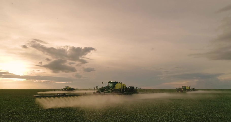 Agriculture, detail of the spray bar, beautiful aerial image of machines spraying soybeans in the open field with beautiful sunset - Agribusiness. Royalty-Free Stock Footage #1047539956