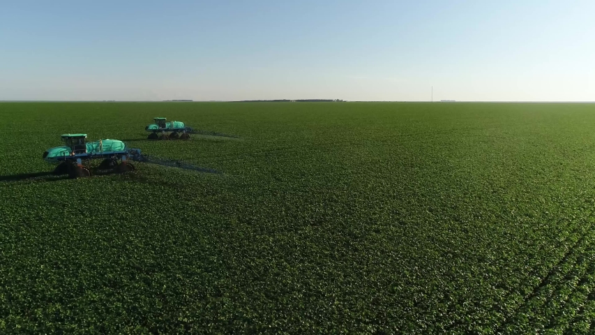 Agriculture, beautiful aerial image of machines spraying soybean plantation in the open field with circular motion - Agribusiness. Royalty-Free Stock Footage #1047540004