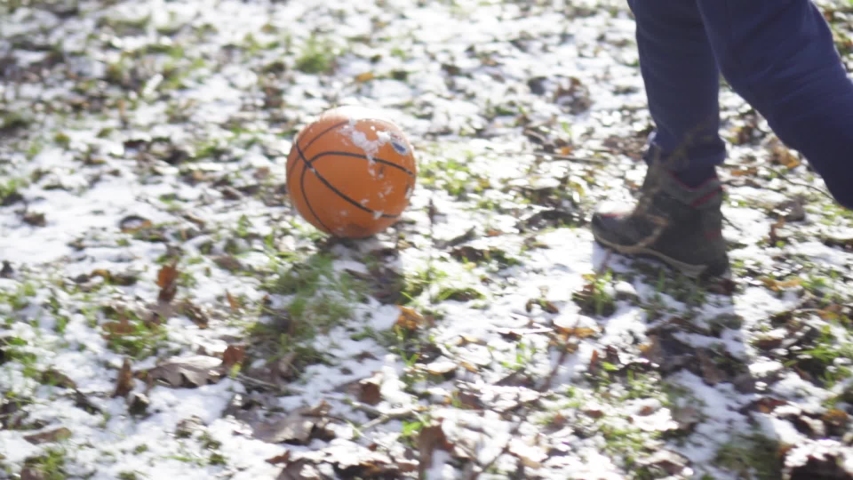 A boy plays with a basketball in the snow. Children