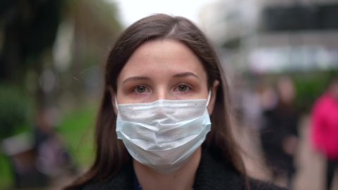 Close up portrait of a caucasian brunette in a protective medical mask on her face. The epidemic of influenza virus and coronavirus is everywhere.