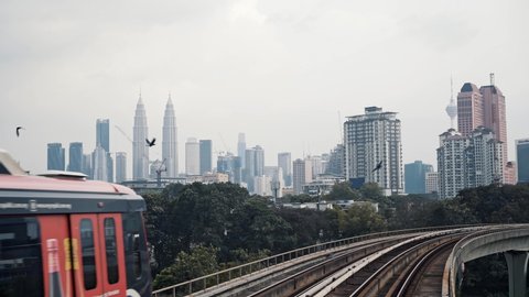 KUALA LUMPUR, MALAYSIA – JANUARY 16, 2020: Locked down real time shot of Kuala Lumpur monorail, LRT Train and modern downtown skyline on background. Public transport in Malaysia.