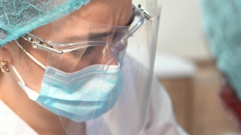 close-up face of a doctor woman in a protective mask, glasses and a medical mask. medic during work. researcher