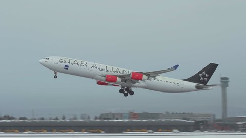 oslo airport norway - ca march 2020: huge airplane airbus 340 take off runway side view scandinavian airlines sas panning left slow motion winter scene