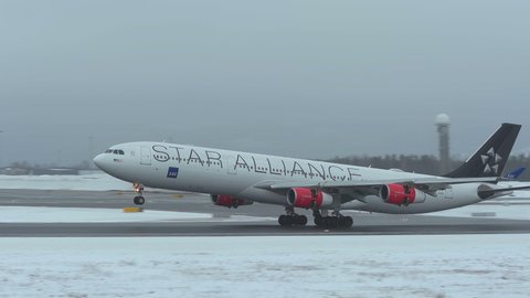 oslo airport norway - ca march 2020: huge airplane airbus 340 arrival side view scandinavian airlines sas panning left winter scene