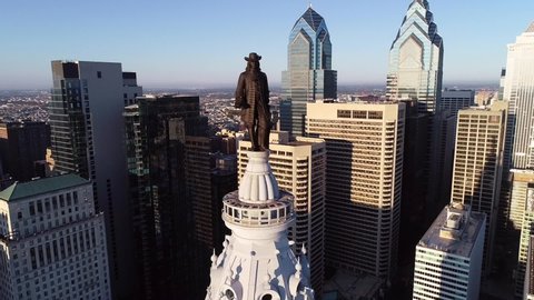 PHILADELPHIA, PENNSYLVANIA - SEPTEMBER 29, 2019: Philadelphia City Hall Tower and bronze statue of William Penn. Cityscape and Beautiful Sunset in Background 