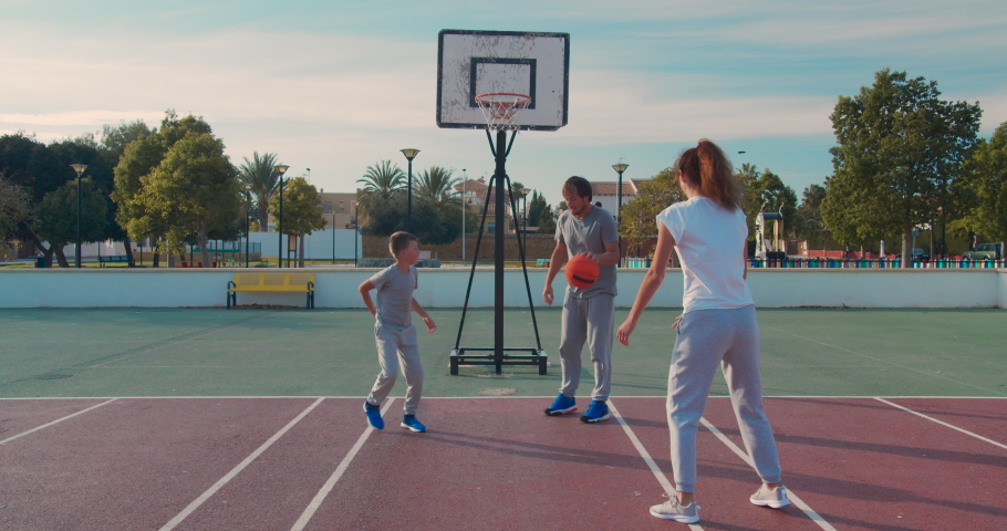 Family playing basketball on outdoor court .