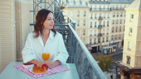 Attractive woman in a white shirt having breakfast on the balcony