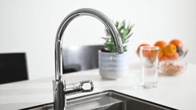 Fresh water running from a tap in a kitchen, there is a fruit bowl in the background, stock footage by Brian Holm Nielsen