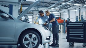 Manager Checks Tasts on a Tablet Computer and Explains an Engine Breakdown to an Female Mechanic. Car Service Employees Inspect Car's Engine Bay with a LED Lamp. Modern Clean Workshop. - Powered by Shutterstock - Get 15% off with code: PIKWIZARD15