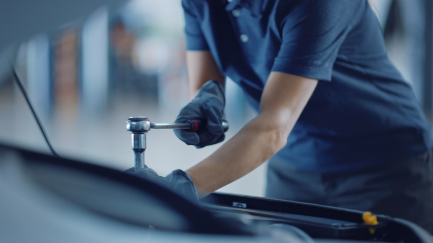 Slow Motion Close Up Footage of a Female Mechanic Working on a Car in a Car Service. Empowering Woman Makes an Usual Car Maintenance. She's Using a Ratchet. Modern Clean Workshop. Royalty-Free Stock Footage #1047624712
