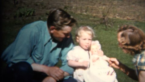 IOWA, USA - JULY 1952: Dad Mom & Baby at Farm Picnic where chickens roam just behind the fence. Redaktionell stockvideo