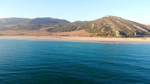 Drone shot of mediterranean beach and sea coast of Zahara de los Atunes taken from the ocean with mountains as background. Cadiz, Andalusia.