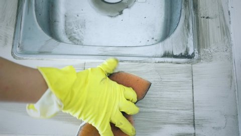 Close up of male worker hands scrubbing dirty kitchen sink with a sponge in the unused house. Shot in 4k resolution