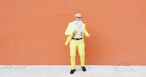 Senior man hipster with funny colored outfit on colored backgrounds