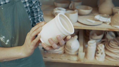 
girl examines pottery mug or glass made of clay close-up
