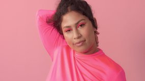 portrait of native american mixed race plus size model in studio on pink with neon pink eye makeup and hair blowing