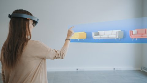 Decorating Apartment: Pretty Woman Wearing Mixed Reality Headset Uses Augmented Reality Interior Design Software to Choose Type and Color of the Furniture for Living Room. 3D Render