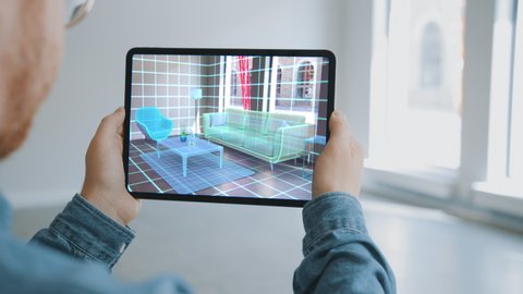 Decorating Apartment: Man Holding Digital Tablet with Augmented Reality Interior Design Software Chooses 3D Furniture for Home. Man Pick Sofa, Table and Lighting for Living Room. Over Shoulder Screen , videoclip de stoc