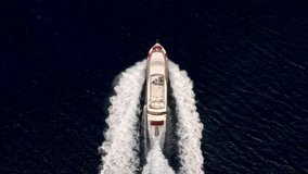 Aerial - tracking top down video of fast moving expensive yacht driving full speed cruising at sea. 4K