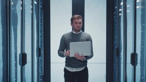 Server specialist works on laptop in server corridor analyzing neural network software of server racks doing maintenance tests at professional secure datacenter. - Powered by Shutterstock - Get 15% off with code: PIKWIZARD15
