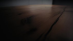 Close up of polished wooden table and the mooving light beam on its surface. Stock footage. Natural wooden texture under the light source.