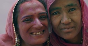 Close-up of a gorgeous Indian female lesbian couple, as they shower each other with kisses celebrate share festival of Holi in India, look at camera pose photo video selfie romance flirt love sisters