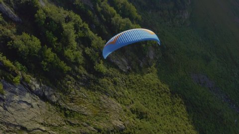 Aerial top view paradlider flying above mountain. Blue parachute and green landscape. outdoor activity