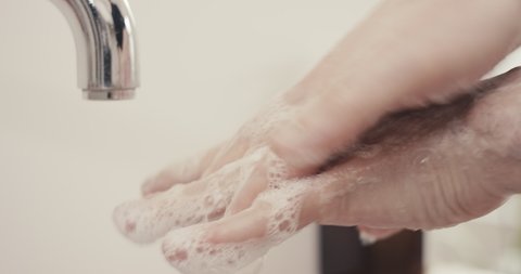 Man washing hands the best way at home rinse with water rub with soap dry with towel extreme close up