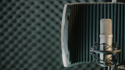 Pan shot of a sound-isolating panel with professional microphone in the studio. Recording concept.