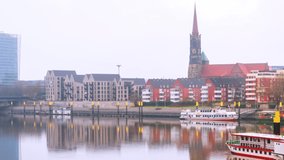 Bremen, Germany. View of the cityscape of Bremen, Germany at morning. Historical landmarks and river, reflection in the water. Time-lapse with boats, panning video