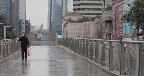 Chengdu, Sichuan/China-March 2rd 2020: One man wear protective mask walking in the empty quiet street talking on the phone at Chunxi road commercial town as coronavirus Covid-19 outbreak