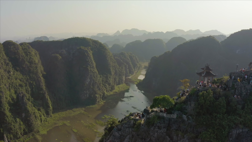 Tourists climb the famous Lying Dragon Mountain Statue during a beautiful sunset in the Ninh Binh province in Northern Vietnam