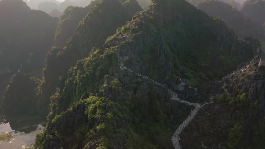 Tourists climb the famous Lying Dragon Mountain Statue during a beautiful sunset in the Ninh Binh province in Northern Vietnam