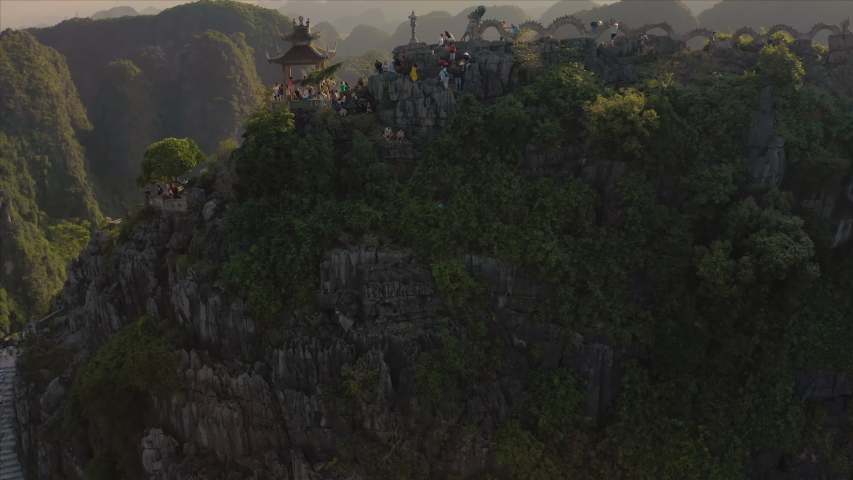 Tourists climb the famous Lying Dragon Mountain Statue during a beautiful sunset in the Ninh Binh province in Northern Vietnam