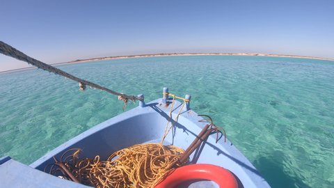 Fishing boat sails through crystal clear blue waters near the Umluj island group in Saudi Arabia
