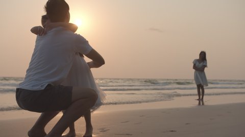 Happy family father and daugther hug and kiss each together on beach and sea with sun flare in evening. Family, Freedom, Relationship, embrace and Travel concept. Positive emotion and feeling warm.